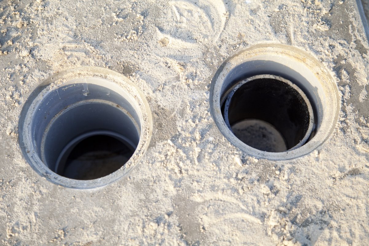 <p>De doppen zijn er even van afgehaald. De twee aparte leidingen voor het regenwater en het perssap liggen 16 tot 17 centimeter dieper, onder een flinke laag gewapend beton.</p>